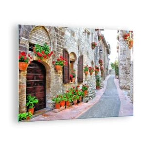 Obraz na skle - Malebná ulica s kamennými múrmi a červenými kvetmi - 70x50cm - Talianska atmosféra - Moderná nástenná dekorácia do obývacej izby a spálne ARTTOR