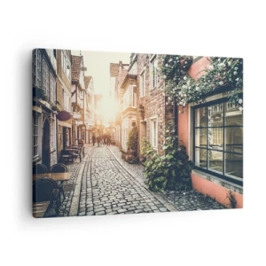 Obraz na plátne - Očarujúca ulica s kamennou dlažbou a kvetmi - 70x50cm - Ružová ulička v ružovej žiare - Moderná nástenná dekorácia do obývacej izby a spálne ARTTOR